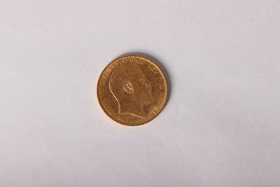 a gold coin on a white surface with a small piece of paper in front of it