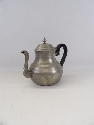 an antique silver teapot with a black handle on a white surface
