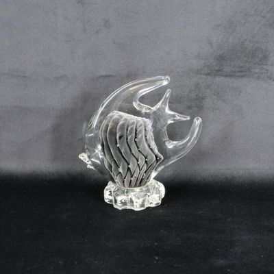 une figurine en verre représentant un poisson posée sur un fond noir