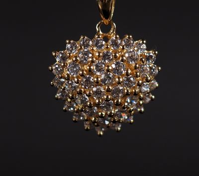 a gold pendant with a cluster of white diamonds on a black background