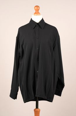 une chemise noire posée sur un mannequin, sur fond blanc