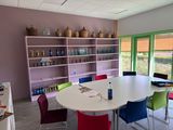brightly colored chairs around a round table in a room with open shelves