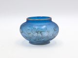 a blue glass vase with a gold rim sitting on a white surface