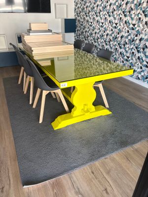 une table en verre avec un piètement jaune au milieu d'une pièce