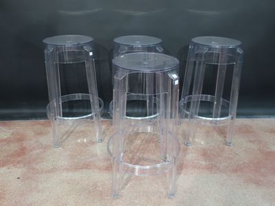 trois tabourets en plastique transparent posés sur un sol recouvert de moquette