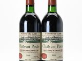 two bottles of red wine sitting next to each other on a white surface