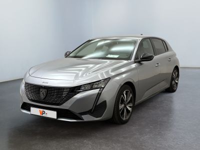 La voiture argentée est garée dans une grande pièce au sol noir.
