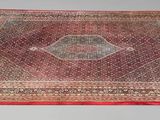 tapis posé sur une table, sur fond blanc et bordé d'un liseré rouge