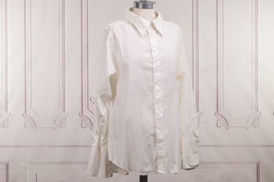 une chemise blanche posée sur un mannequin devant un mur