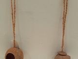 two small wooden bells hanging from a rope on a wall