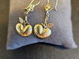 boucles d'oreilles en forme de pomme, en argent et en or, posées sur un coussin gris