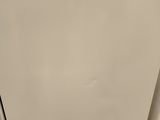 an image of a white refrigerator in the corner of a room