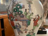 a white vase with a painting on it on a table