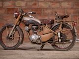 a old motorcycle that is parked in front of a brick wall