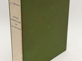 an old book with a green cover sitting on top of a white table