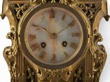a gold clock with roman numerals on the face