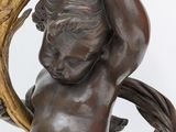 bronze statue of a boy holding a mirror in his hands