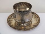 a silver cup and saucer on a saucer on a white table
