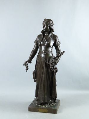 une statue antique en bronze représentant une femme tenant un panier de fleurs