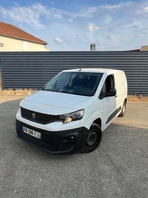 une camionnette blanche garée sur un parking près d'une clôture