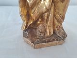 a gold statue of a woman sitting on top of a rock