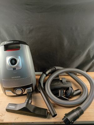 un aspirateur posé sur une table, muni d'un tuyau