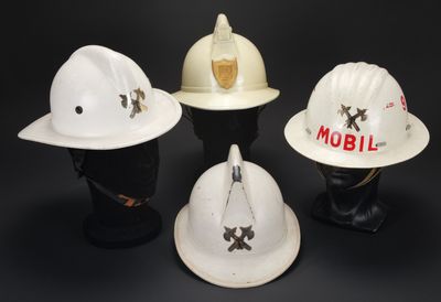 trois casques de chantier blancs empilés les uns sur les autres sur une surface noire