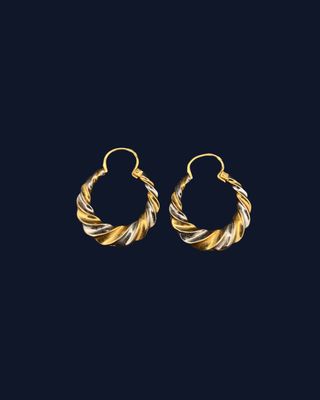 a pair of gold and silver hoop earrings on a black background