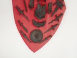a red shield with a lot of metal items on it