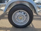 a silver trailer with a flat tire on a parking lot
