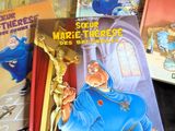 Plusieurs livres pour enfants sont posés sur une étagère devant une bougie