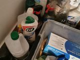 a lot of cleaning supplies in a bin on the counter