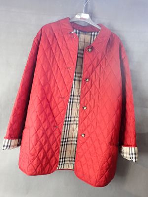 une veste matelassée rouge suspendue à un cintre accroché au mur
