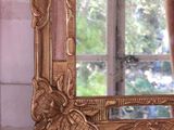 a mirror sitting on a window sill with a chandelier in the background