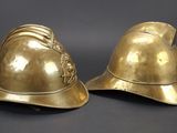 pair of antique brass fire helmets on a black background