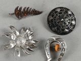 three silver brooches and a silver broochle on a table