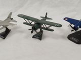 three small model airplanes sitting on top of each other on a white surface