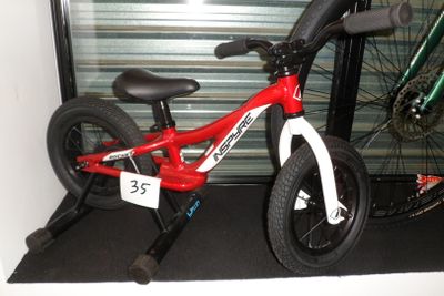 un vélo rouge et blanc exposé devant la porte d'un garage