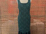 a green dress on a mannequin stand in front of a woven wall