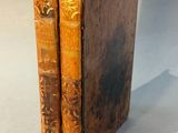 two old books are stacked on top of each other on a table