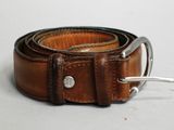 ceinture en cuir marron avec une boucle argentée sur un fond blanc