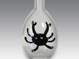 a glass vase with a black spider inside of it