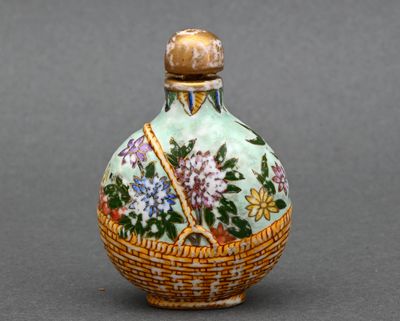 une petite bouteille en verre ornée d'un panier de fleurs
