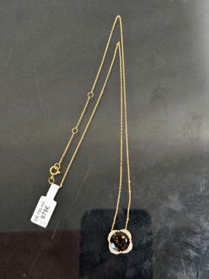 un collier en or avec un pendentif en pierre marron et une petite plaque accrochée dessus