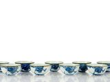Plusieurs bols et tasses bleus et blancs sont alignés sur une surface blanche