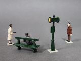 two figurines of people sitting on a bench next to a traffic light