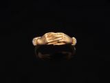 an image of a gold ring with two hands on it