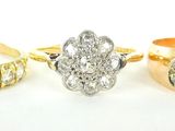 trois bagues en or et en argent, ornées de diamants, posées sur un fond blanc