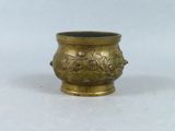 an image of a small brass vase with flowers and leaves on it