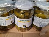 Plusieurs bocaux de cornichons sont posés sur une étagère dans un magasin